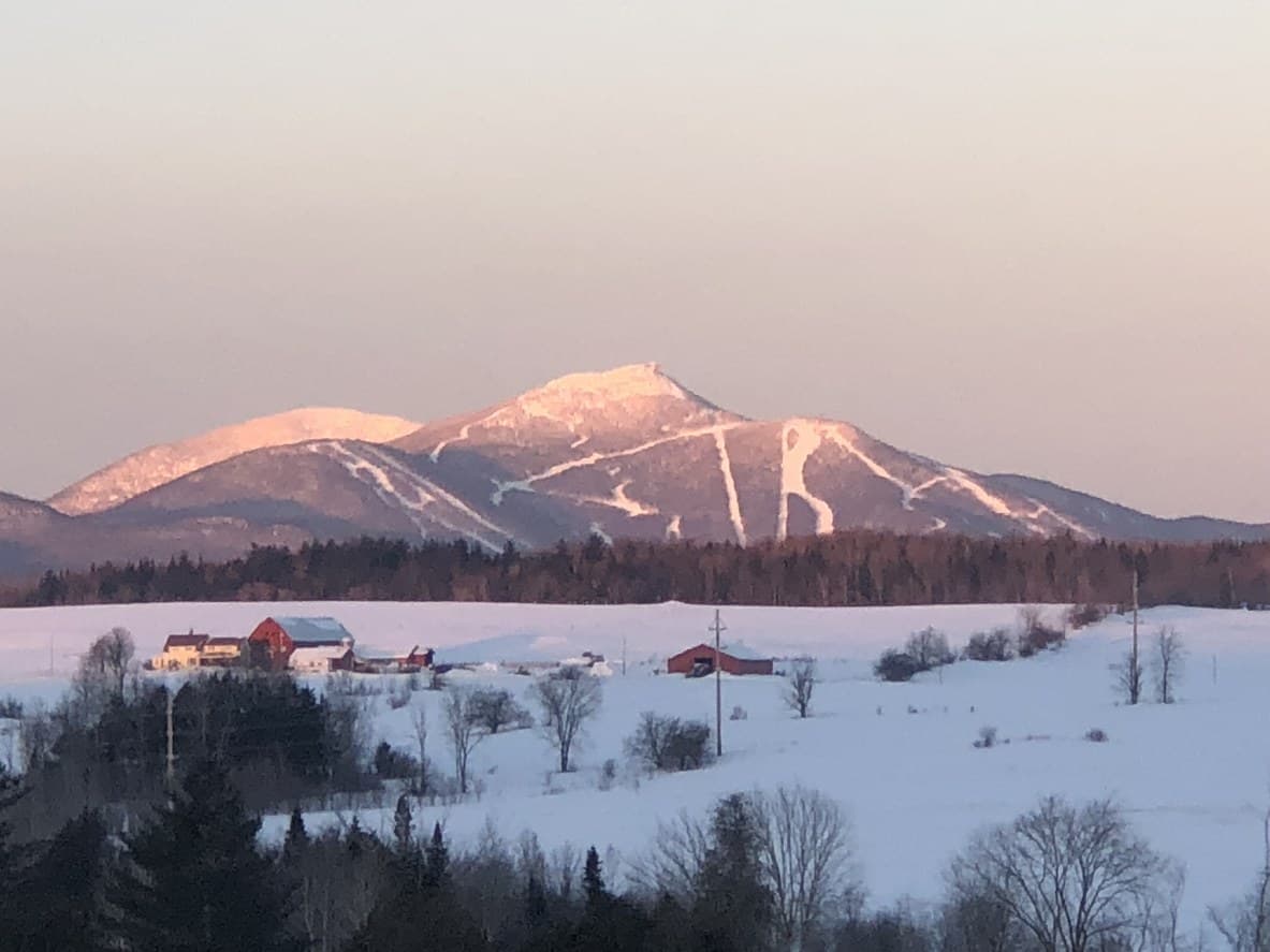 Jay Peak at sunset, with snow-covered ski trails glowing pink above the rural Vermont landscape Vermont Electric Cooperative serves.